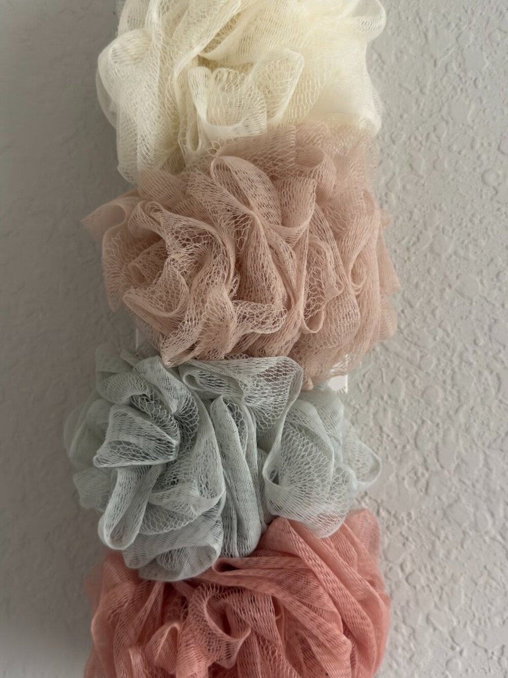 A set of four shower sponges in soft pastel colors